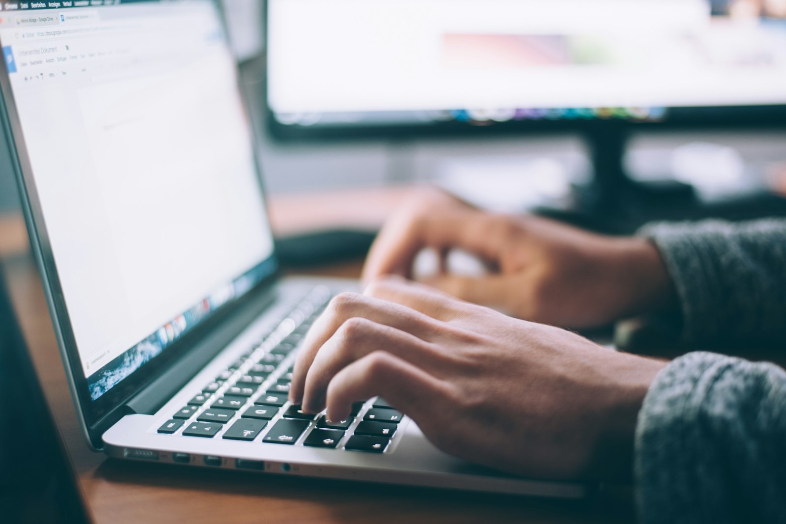 Hands writing an email at a laptop